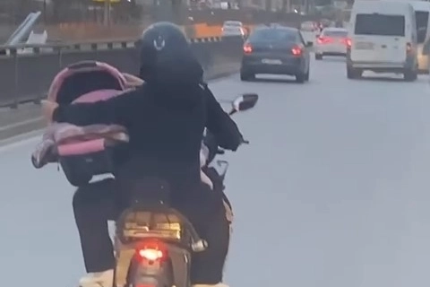 Motosiklet üzerinde bebeği pusetiyle taşıdı