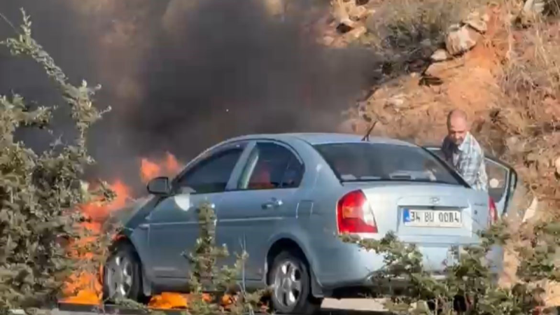 Alev alan otomobilini kurtarmak için çabaladı